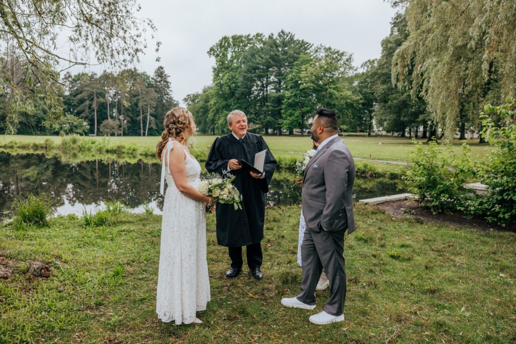 Bride and groom standing out with officiant for summer wedding at Bird Park in Walpole, Massachusetts.