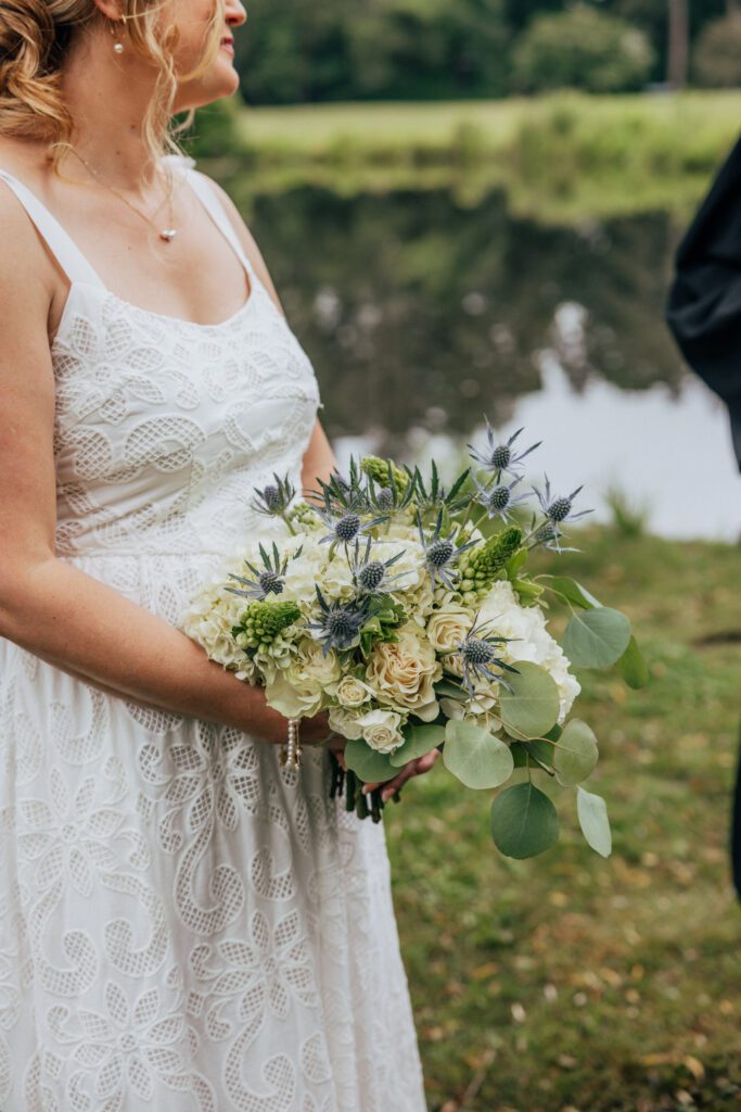 Bride holding summer bouquet during whimsical outdoor wedding at Bird Park in Walpole, Massachusetts