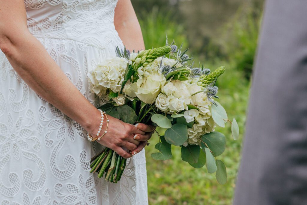 Bride holding white and blue bouquet during elopement ceremony at Bird Park in Walpole, Massachusetts.