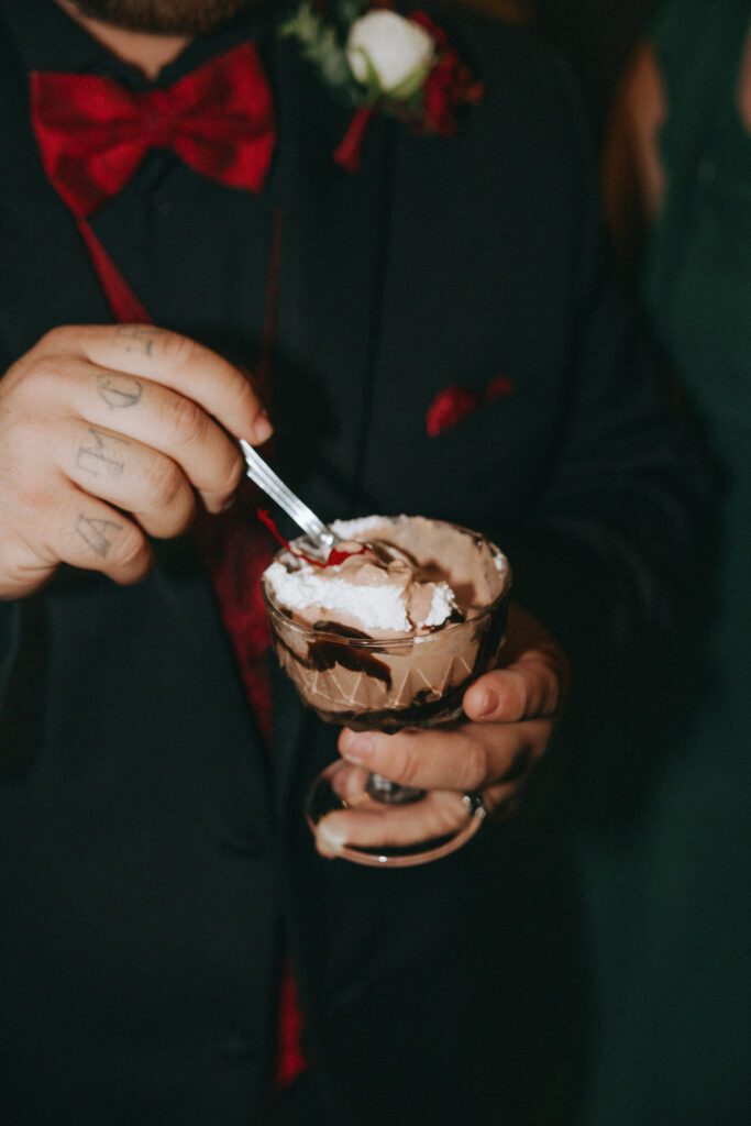 Groom eating from ice cream bar during reception at Black Swan Country Club in Georgetown, Massachusetts.