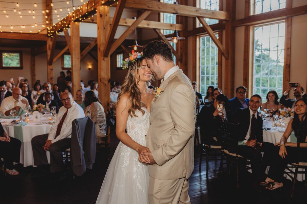 Romantic bride and groom first dance smiling at each other in their summer barn reception at Peirce Farm Estate in Topsfield, Massachusetts.