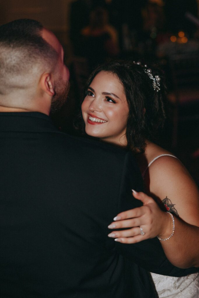 Bride smiling and looking up at groom while they are dancing during the reception at Black Swan Country Club in Georgetown, Massachusetts.