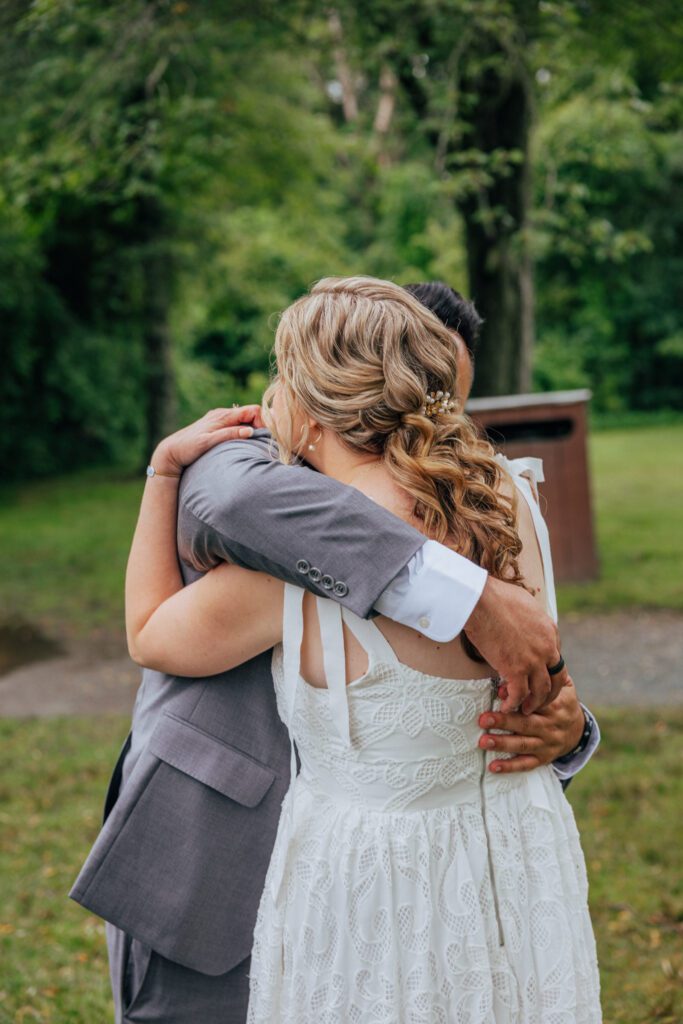 Bride and groom hugging during elopement ceremony surrounded by greenery at Bird Park in Walpole, Massachusetts.