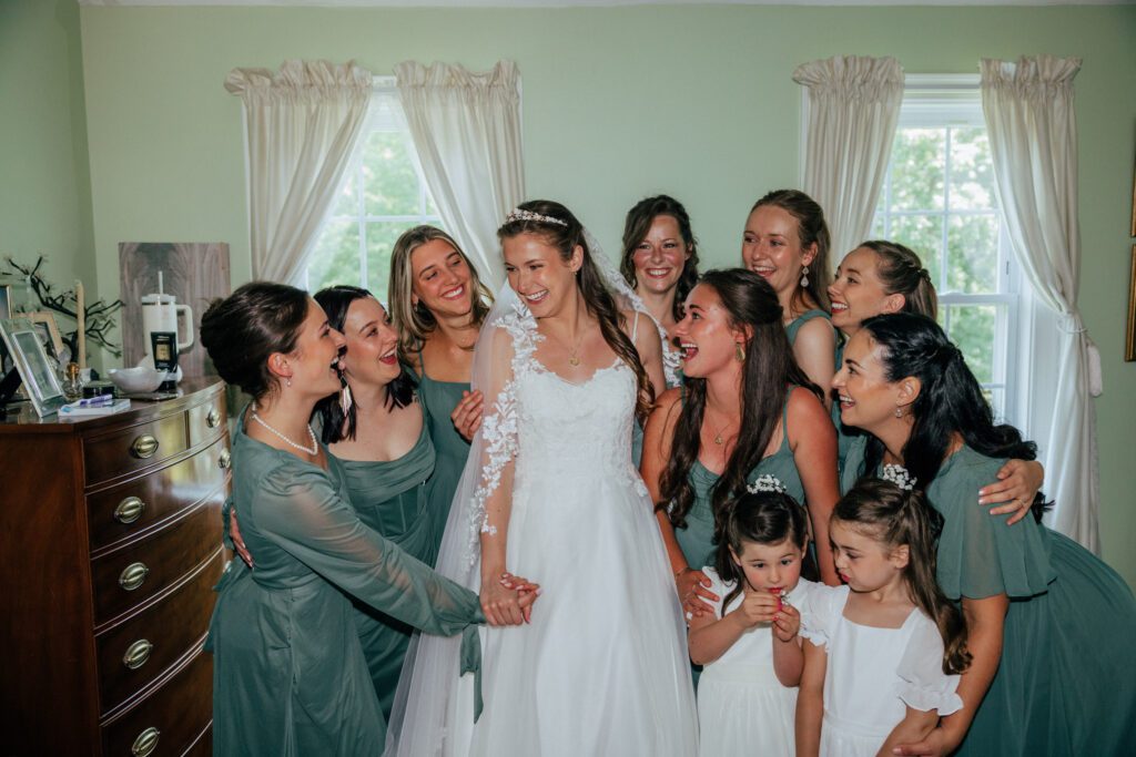 Bride has first look with bridesmaids and they all smile and laugh when they see her for Massachusetts wedding.