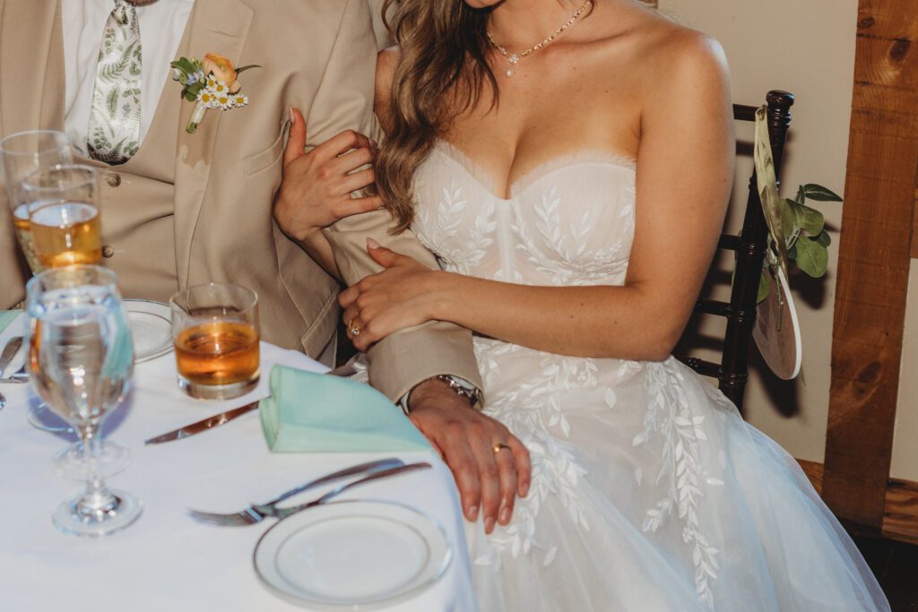 Bride holding onto grooms arm during romantic barn reception at Peirce Farm Estate in Topsfield, Massachusetts.