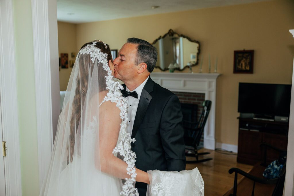 Emotional father of the bride kissing bride on the cheek after first look.