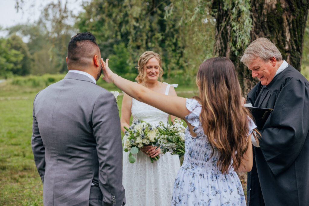 Daughter wiping dads tear away during wedding ceremony at Bird Park in Walpole, Massachusetts.