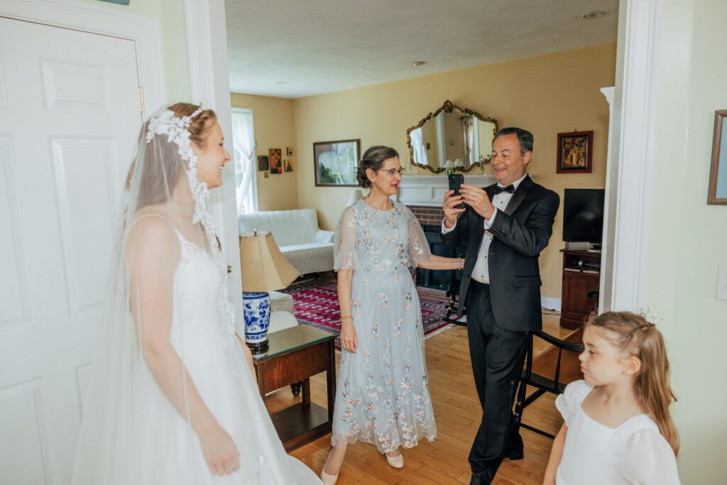 Father of the bride taking a photo of the bride after first look in Massachusetts.