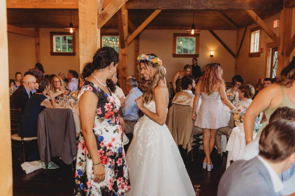 Bride smiling at guest during barn reception at Peirce Farm Estate in Topsfield, Massachusetts.