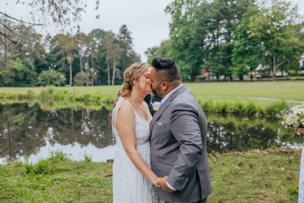Bride and groom kiss during outdoor wedding ceremony at Bird Park in Walpole, Massachusetts.