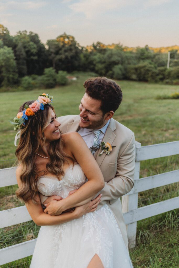 Close up of bride and groom romantically looking at each other as they stand in front of a white fence at Peirce Farm Estate in Topsfield, Massachusetts.