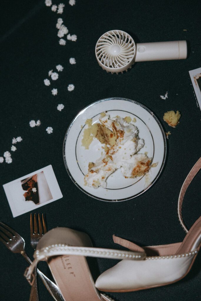 Cake, Polaroid, fan, and wedding shoes on a table showing the end of night vibe at Black Swan Country Club in Georgetown, Massachusetts.