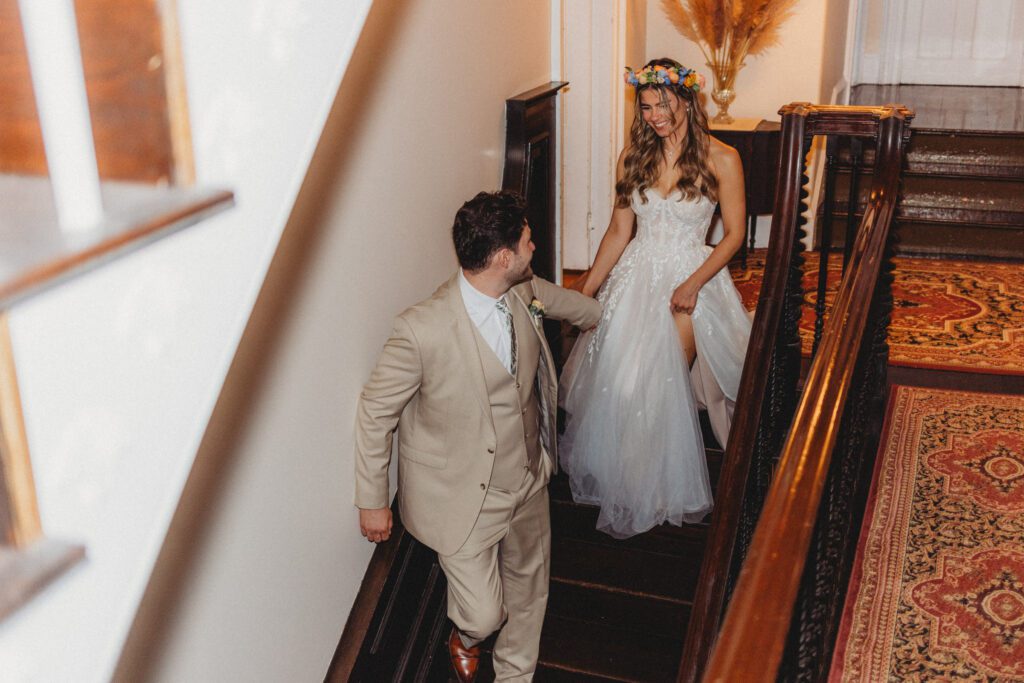 Groom walking down stairs, looking back at bride at Peirce Farm Estate in Topsfield, Massachusetts.