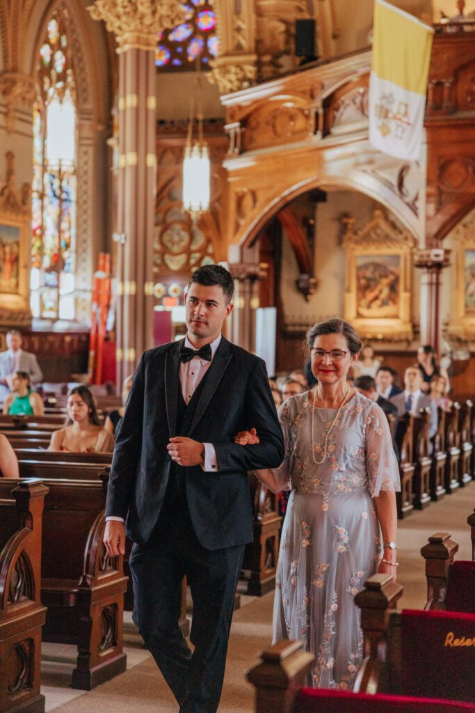 Mother of the bride walking down the aisle during wedding ceremony at Quinet Saint John Garden of Our Lady in Massachusetts.