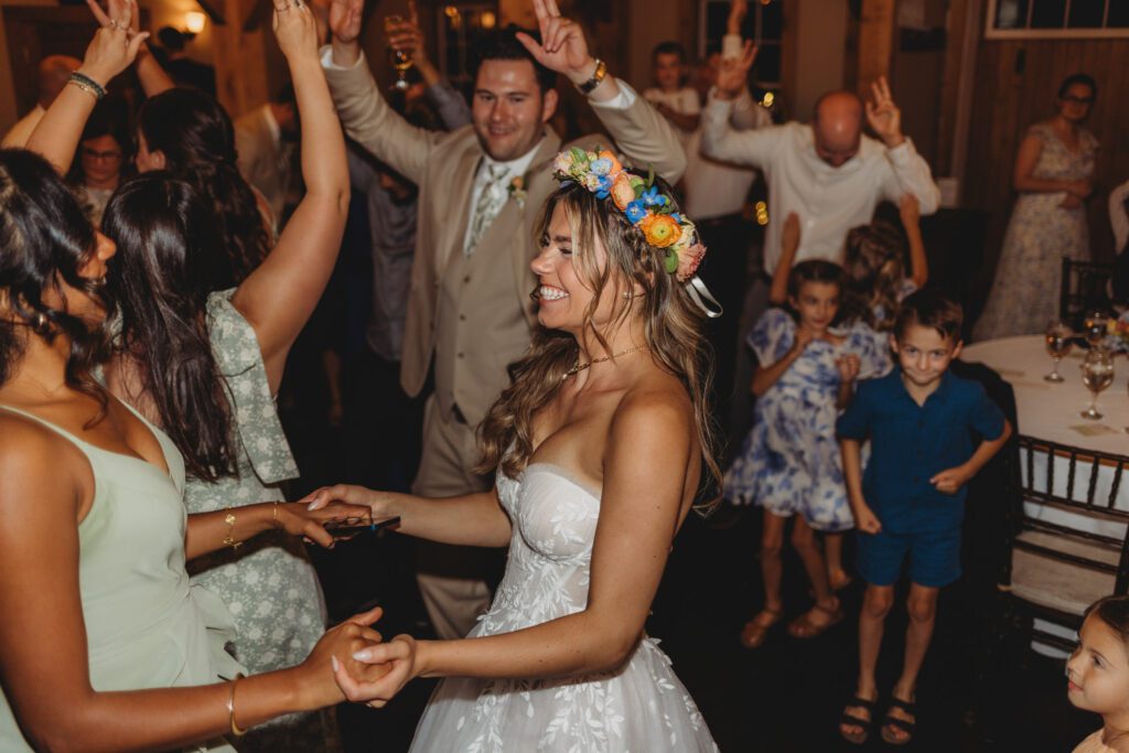 Bride dancing and smiling during barn reception with her bridesmaid at Peirce Farm Estate in Topsfield, Massachusetts.