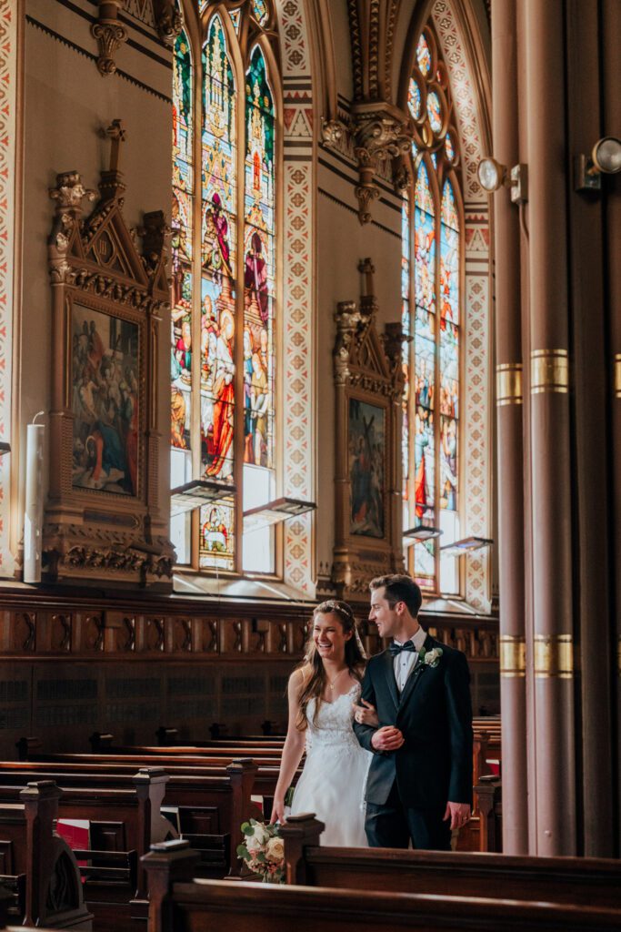 Groom looking at bride as they walk through church at Quinet Saint John Garden of Our Lady in Massachusetts.