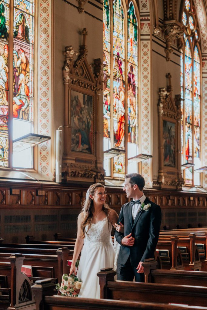 Bride and groom laughing and walking in church at Quinet Saint John Garden of Our Lady in Massachusetts.