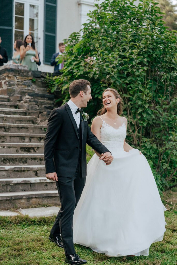 Romantic bride and groom walking down stone stairs laughing together in Massachusetts.
