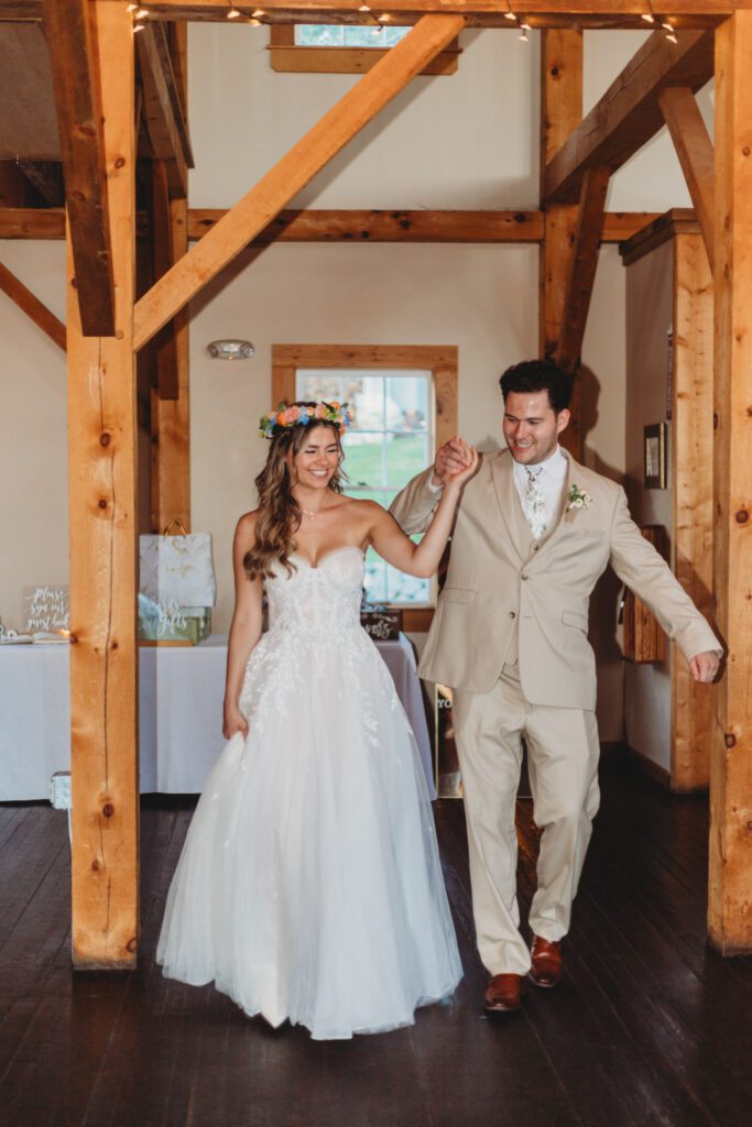 Bride and groom smiling and holding hands as they enter their reception at Peirce Farm Estate in Topsfield, Massachusetts.