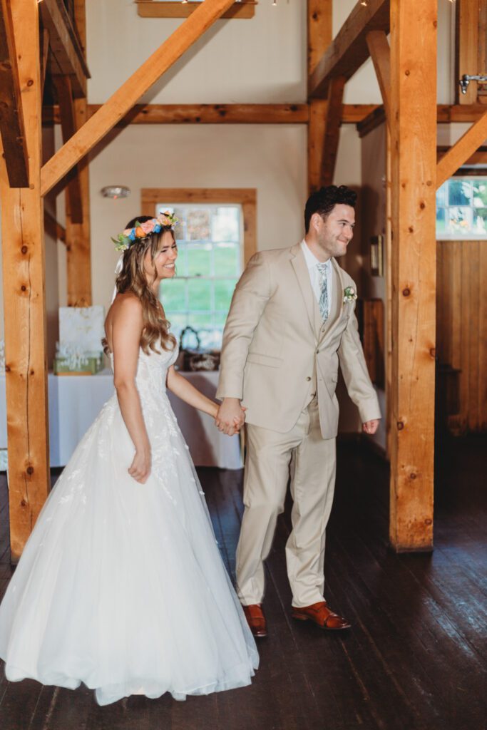 Bride and groom smiling at their guests as they enter a whimsical barn reception at Peirce Farm Estate in Topsfield, Massachusetts.