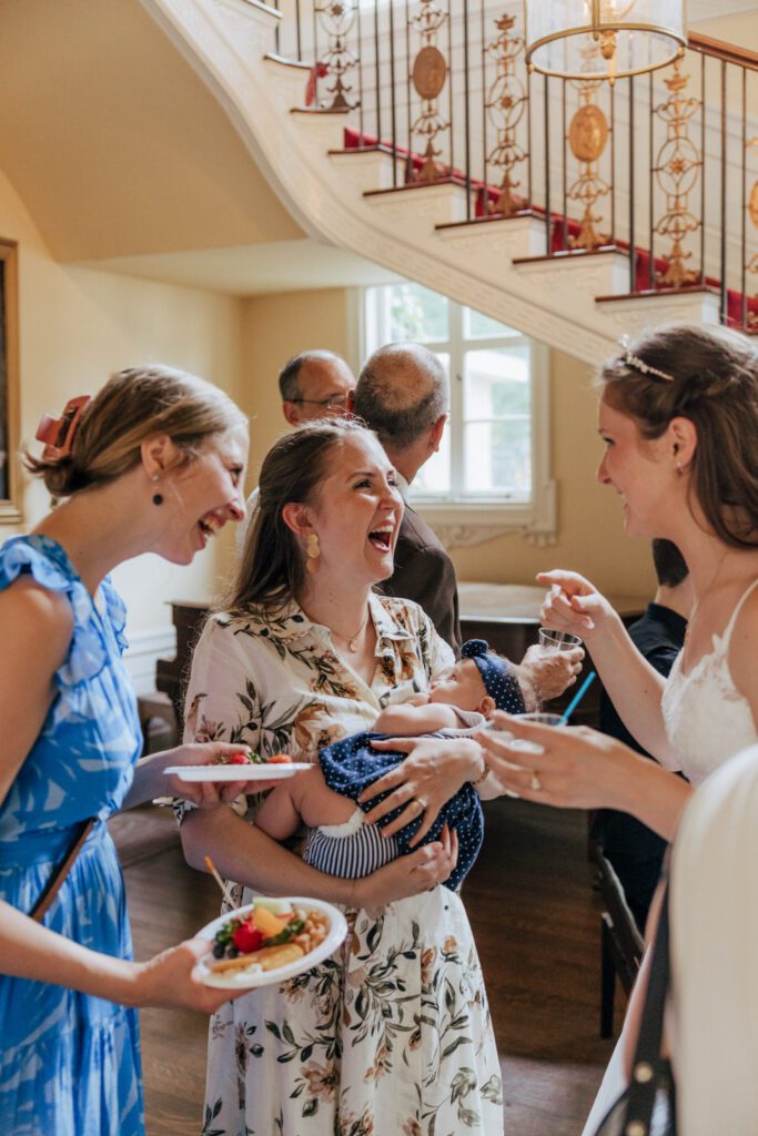 Guests laughing together indoors during wedding cocktail hour in Massachusetts.