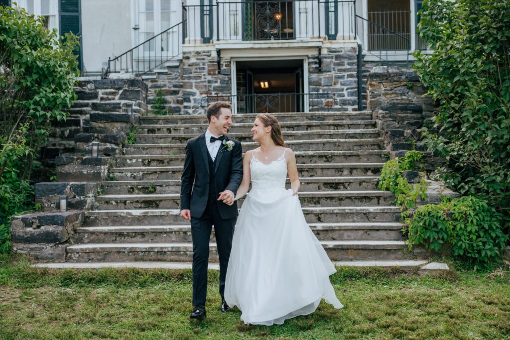 Bride and groom romantically walking down stone stairs in Massachusetts.