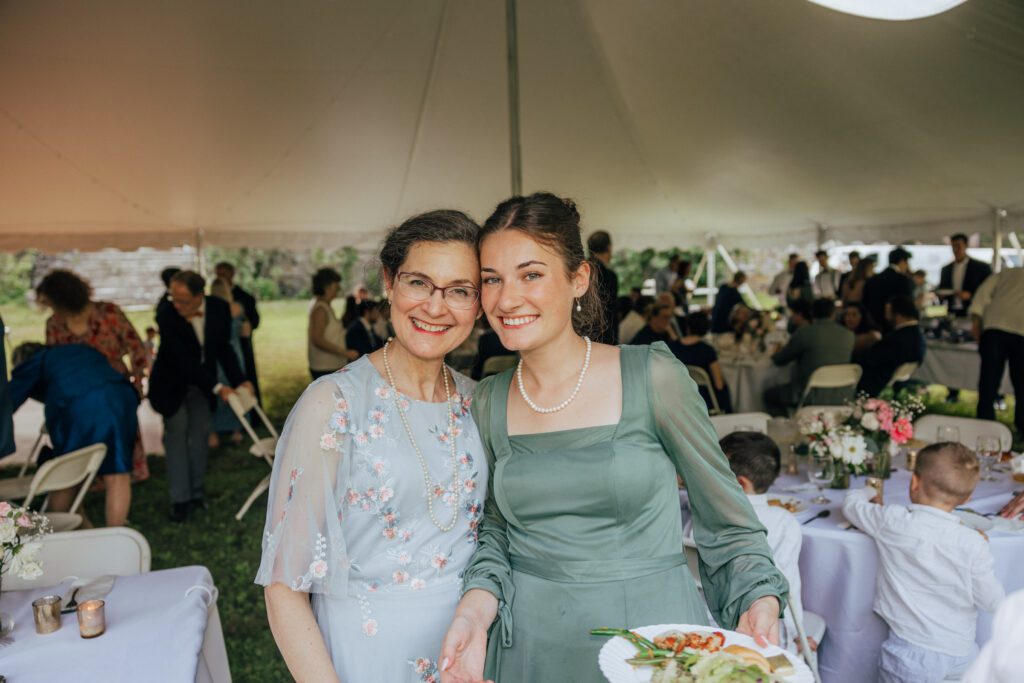 Mother of the bride and bridesmaid smiling during the reception in Massachusetts.