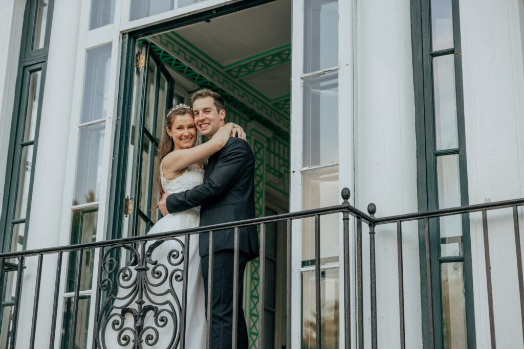 Bride and groom romantically hugging and smiling on balcony in Massachusetts.