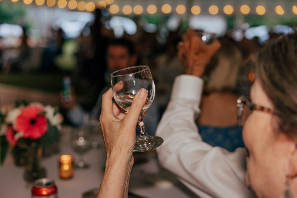 Glass of wine being raised during wedding reception in Massachusetts.