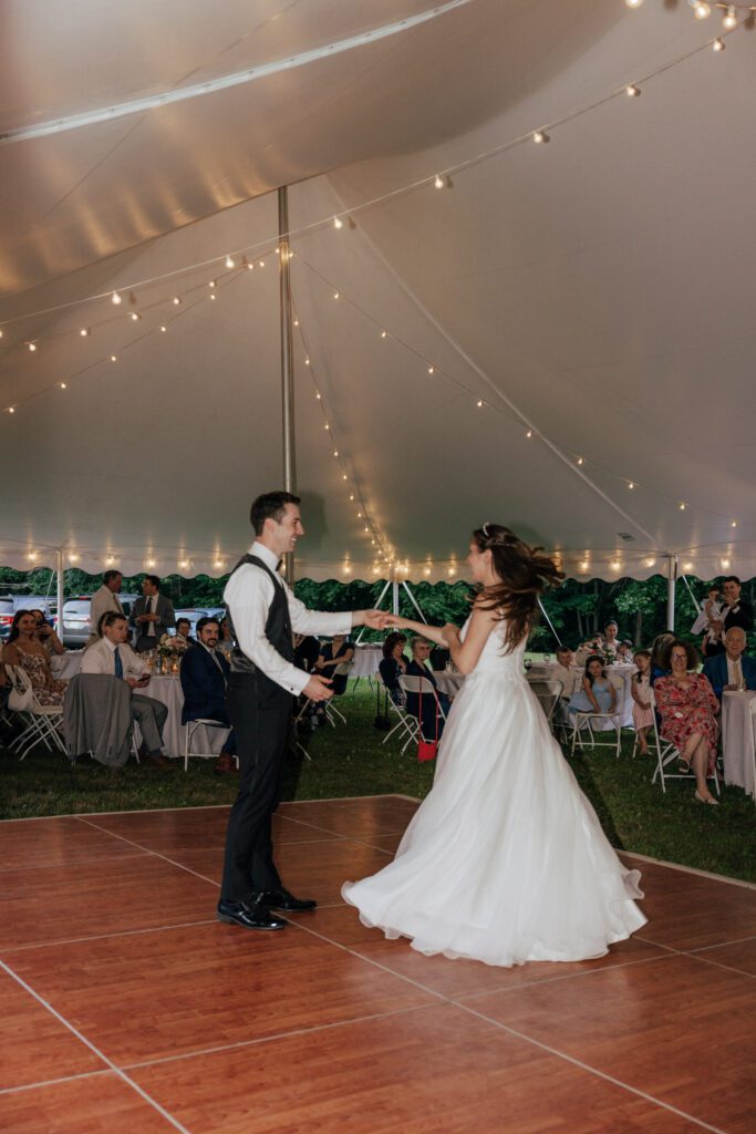 Groom spinning bride during outdoor wedding reception in Massachusetts.