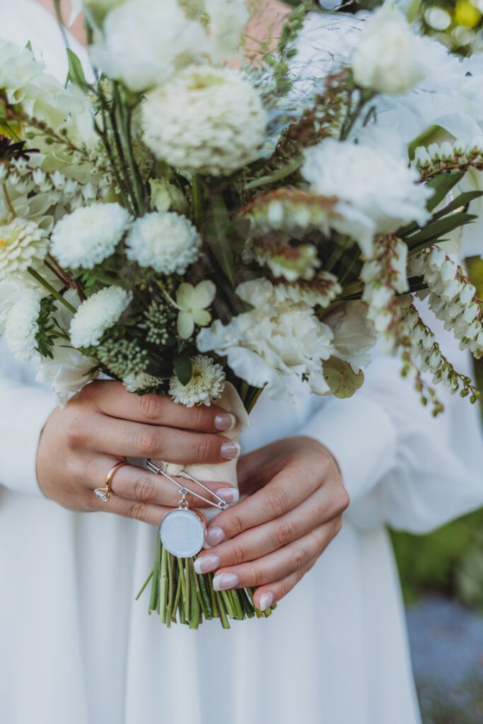 Bride holding white flower bouquet outside in garden at New England Botanical Garden at Tower Hill in Boylston, Massachusetts.
