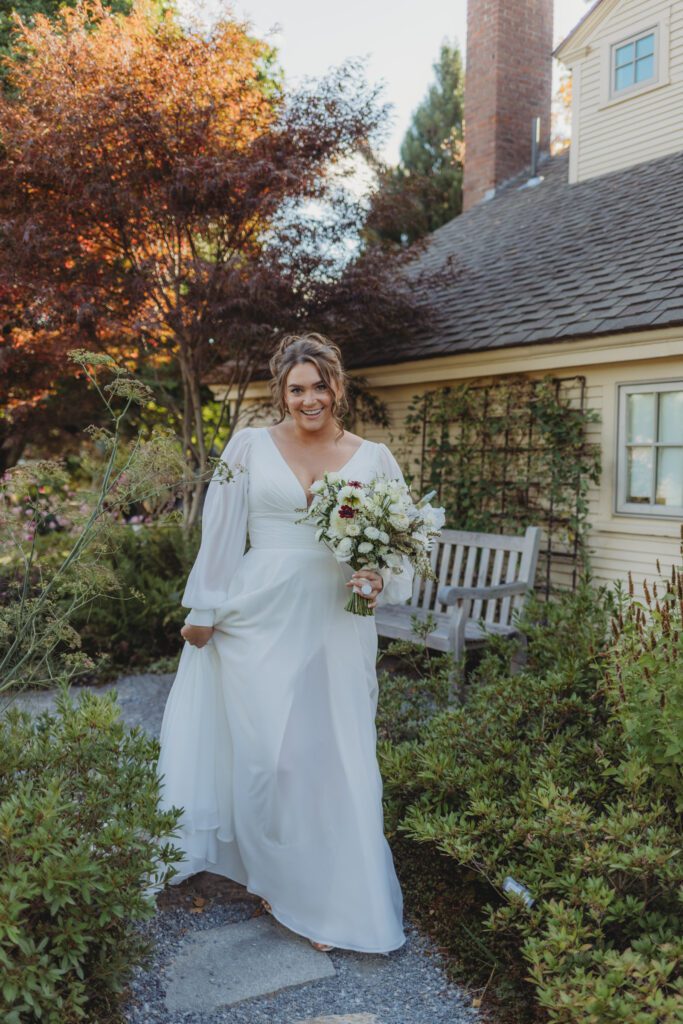 Bride walking through garden holding white bouquet at New England Botanical Garden at Tower Hill in Boylston, Massachusetts.