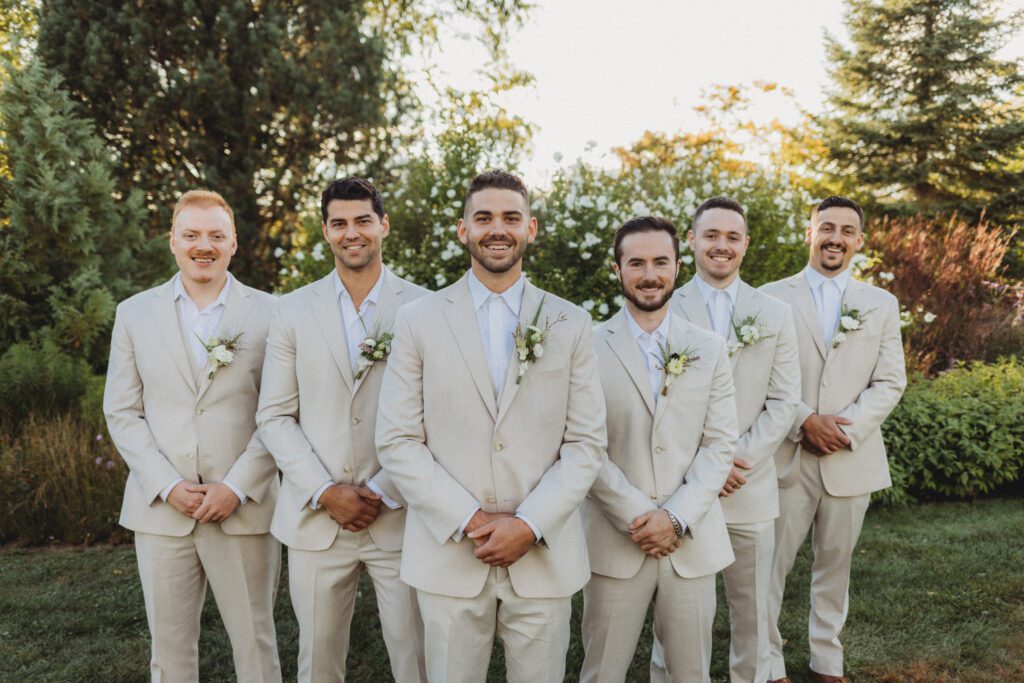 Groomsmen and groom standing in a line and smiling in garden at Tower Hill in Boylston, Massachusetts.