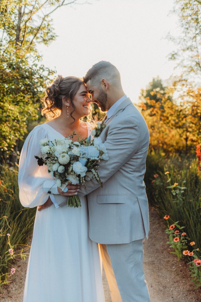 Bride and groom smiling at each other at golden hour as the sun shines behind them at Tower Hill in Boylston, Massachusetts.