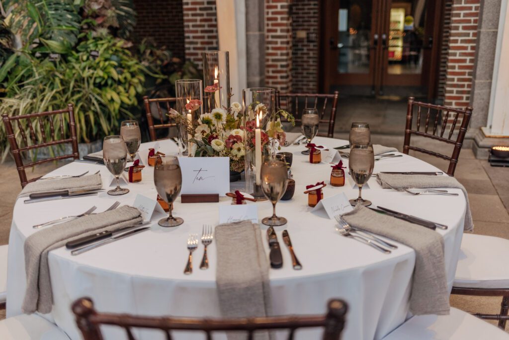 Table decoration including glasses, candles, and flowers for greenhouse wedding reception at Tower Hill in Boylston, Massachusetts.