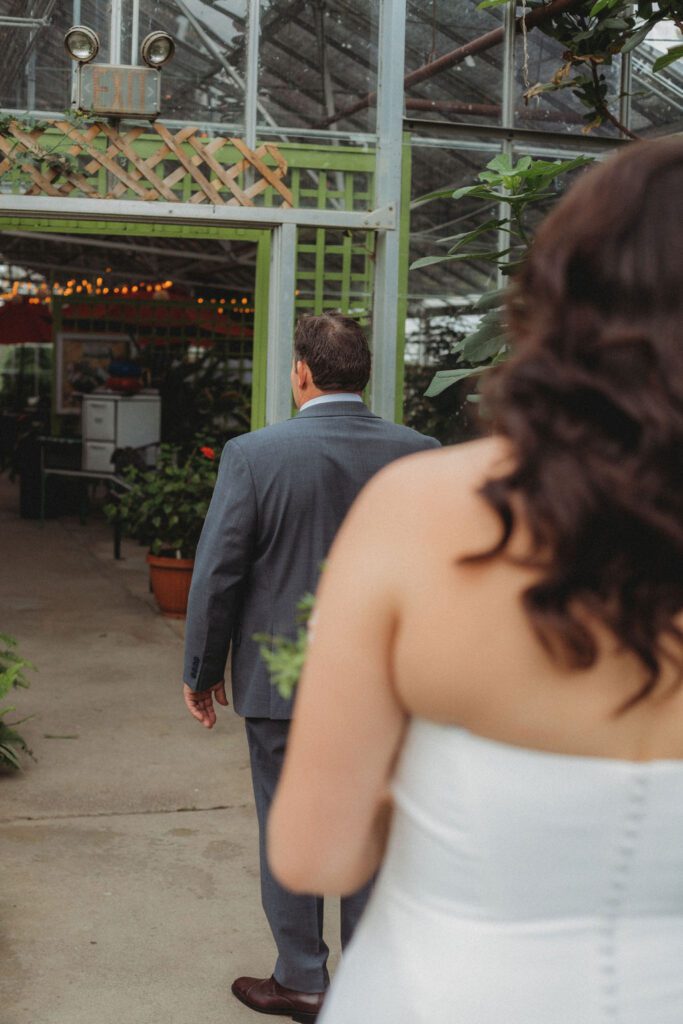 Bride walking to father during first look in a greenhouse at Roger Williams Botanical Garden Park in Providence, Rhode Island.