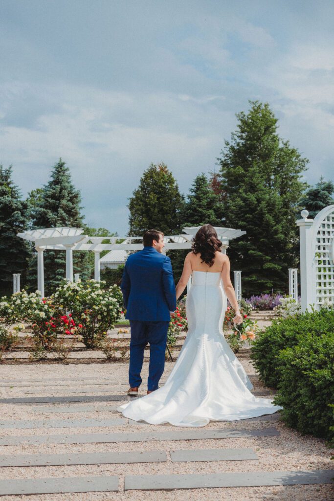 Bride and groom holding hands as they walk into a maze garden at Roger Williams Botanical Garden Park in Providence, Rhode Island.