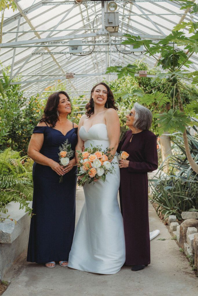 Bride and family smiling in greenhouse at Roger Williams Botanical Garden Park in Providence, Rhode Island.