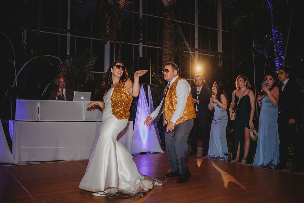 Bride and her father dancing with gold vest during reception in a greenhouse at Roger Williams Botanical Garden Park in Providence, Rhode Island.