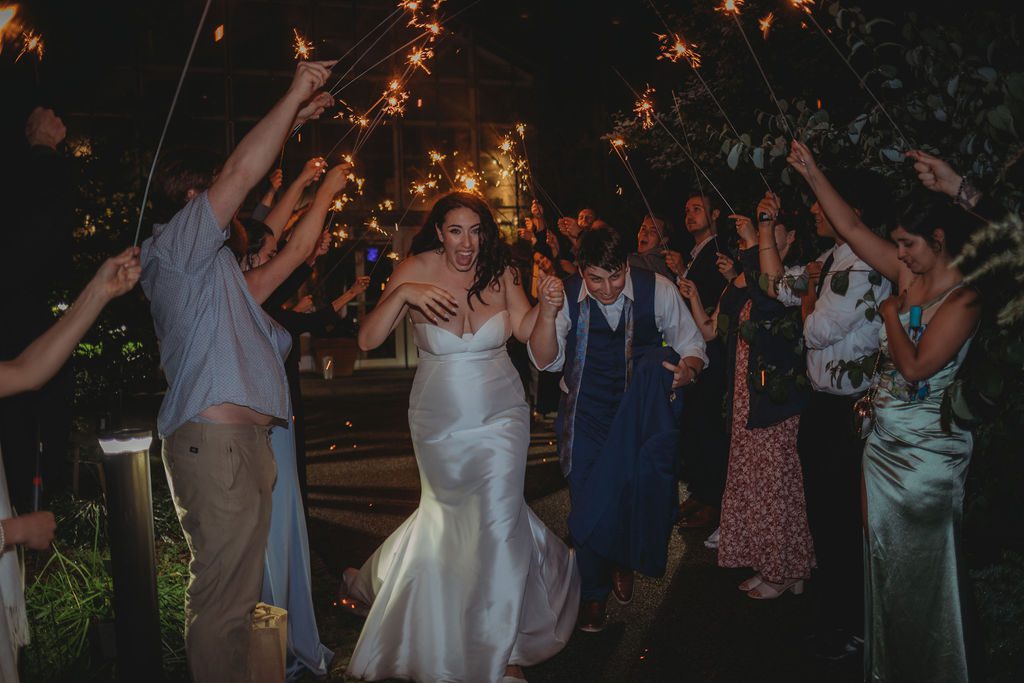Bride and groom exiting their wedding with their guest holding sparklers at Roger Williams Botanical Garden Park in Providence, Rhode Island.