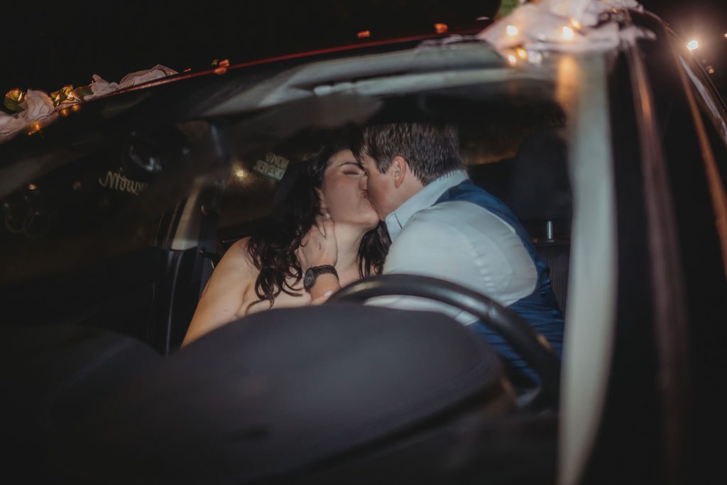 Bride and groom kissing in their get away car after their wedding at Roger Williams Botanical Garden Park in Providence, Rhode Island.