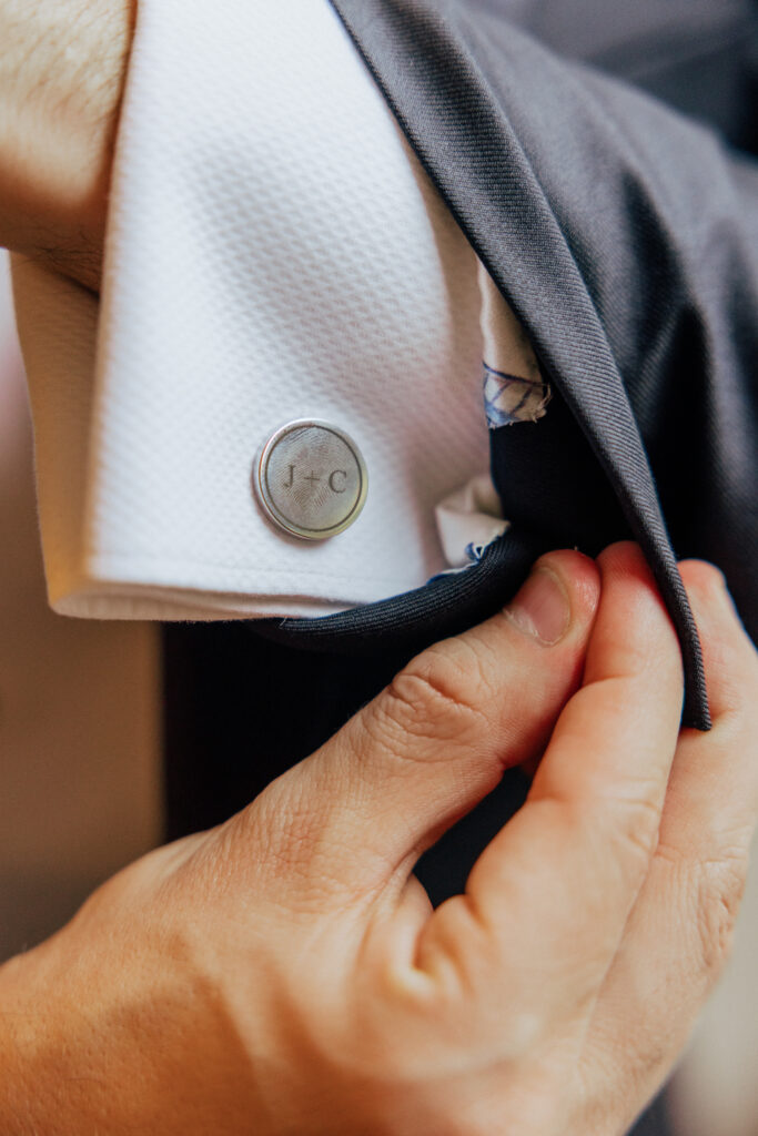 Groom adjusting his suit sleeve with custom cuff pins at The Conner Center in Dover, Massachusetts.