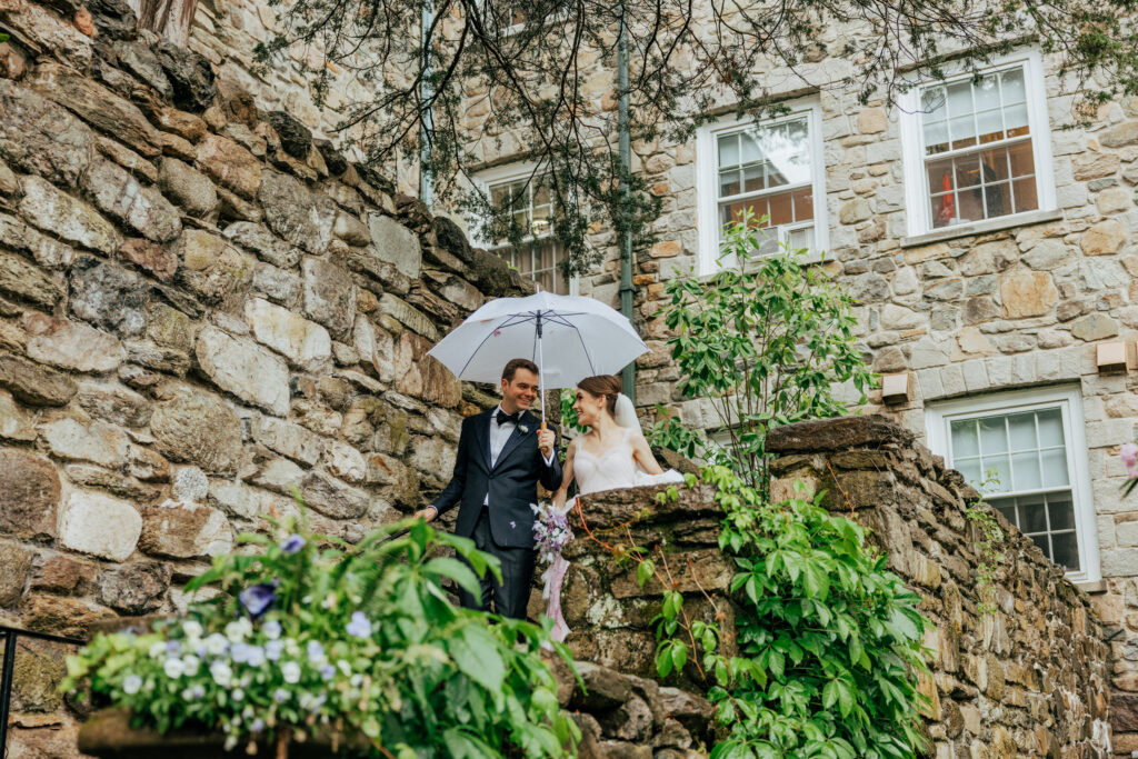 Bride and groom walking down stone staircase looking at each other an laughing at The Conner Center in Dover, Massachusetts.