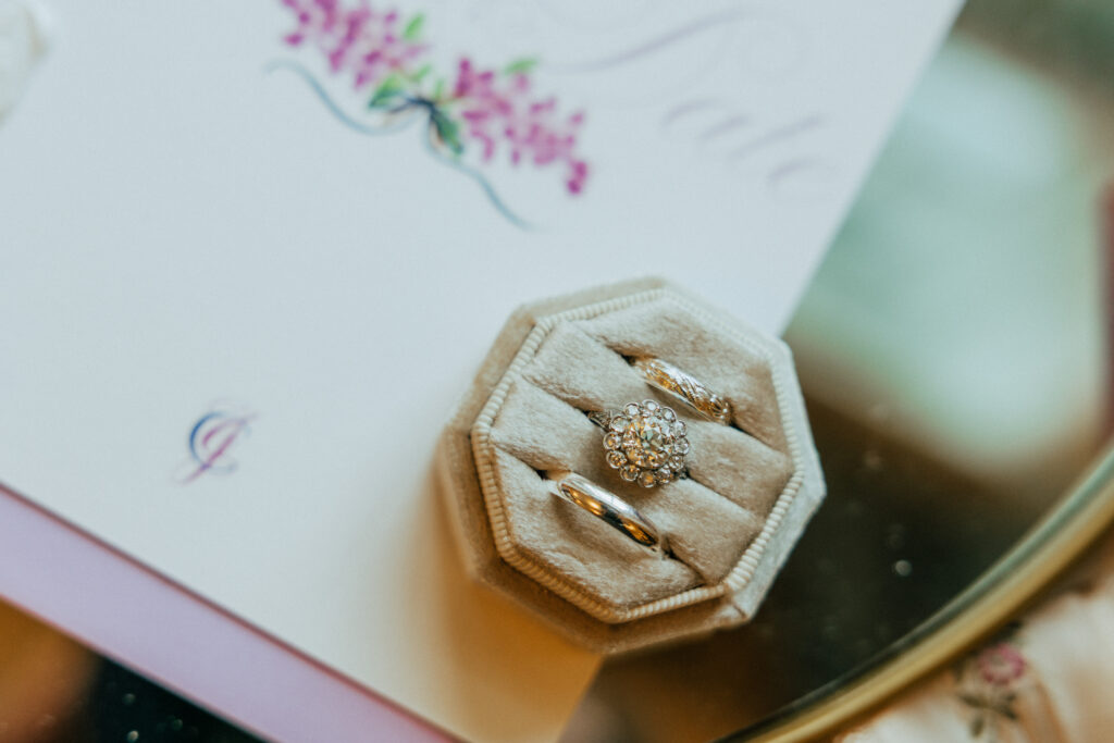 Whimsical flat lay of invitation and rings at The Conner Center in Dover, Massachusetts.