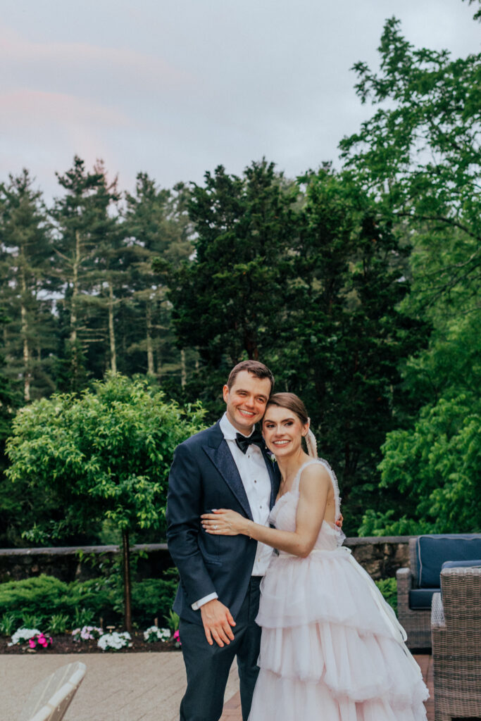 Groom and bride hugging with greenery behind them at The Conner Center in Dover, Massachusetts.